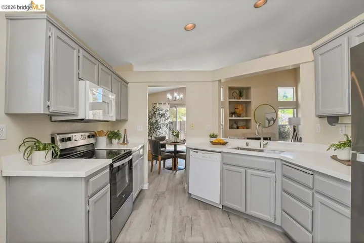 Updated kitchen featuring light gray cabinetry, white countertops, stainless steel appliances, and wood-finish flooring