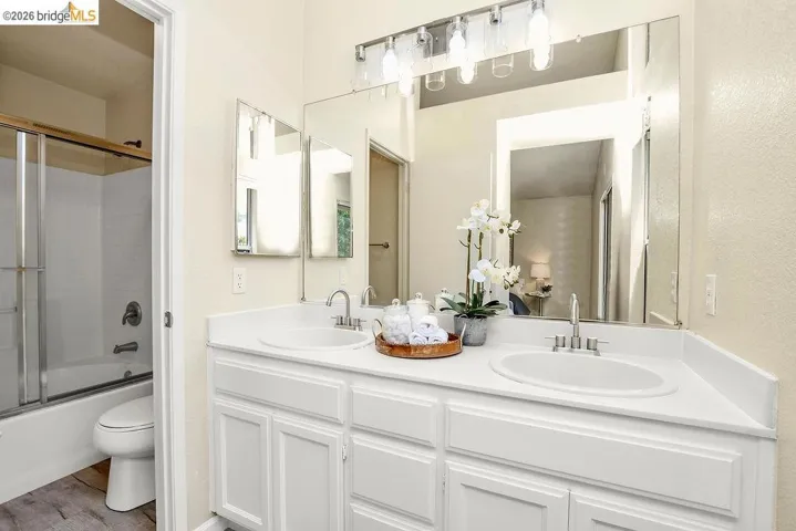 Bathroom featuring a dual-sink vanity with white cabinetry and a full-width mirror