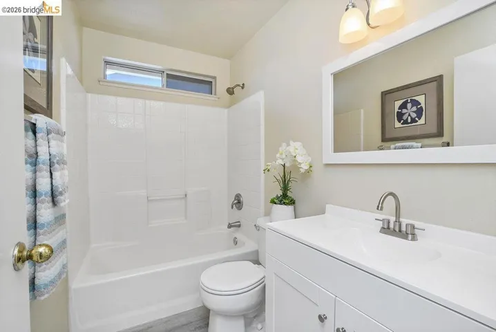 Bathroom featuring a white vanity with integrated sink, brushed nickel faucet, and overhead vanity lighting