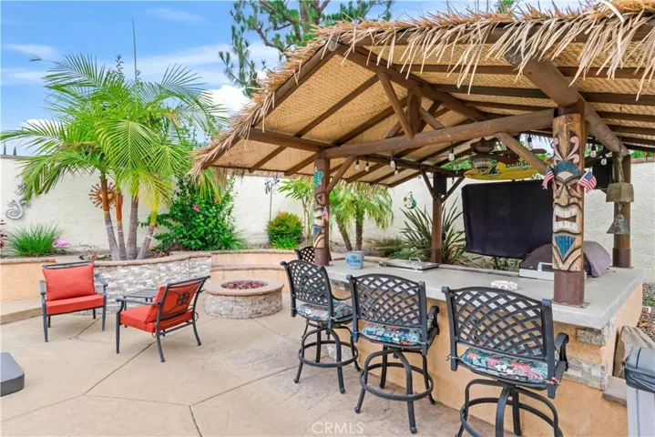 BBQ Tiki area and fire pit next to pool with beautiful landscaping