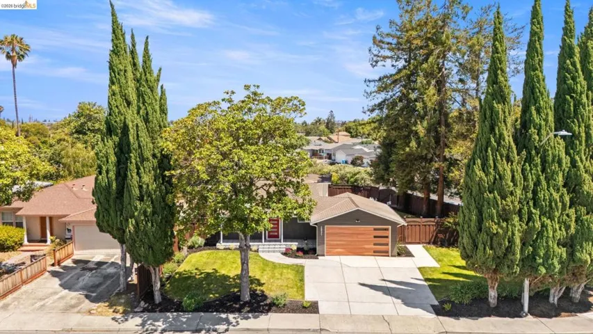 Contemporary residence featuring a wood-panel garage door, dark siding, and a well-maintained front lawn