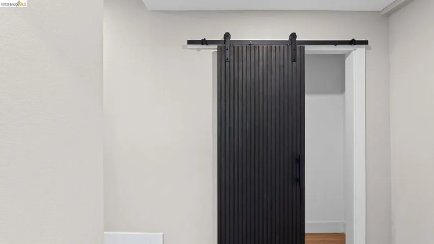 Matte black barn door with vertical fluted detailing and exposed top-mounted hardware