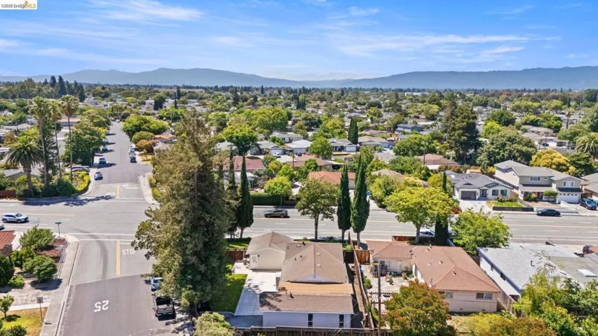 Aerial perspective showcasing a residential neighborhood with a diverse collection of single-story and multi-story homes, mature trees, and paved streets