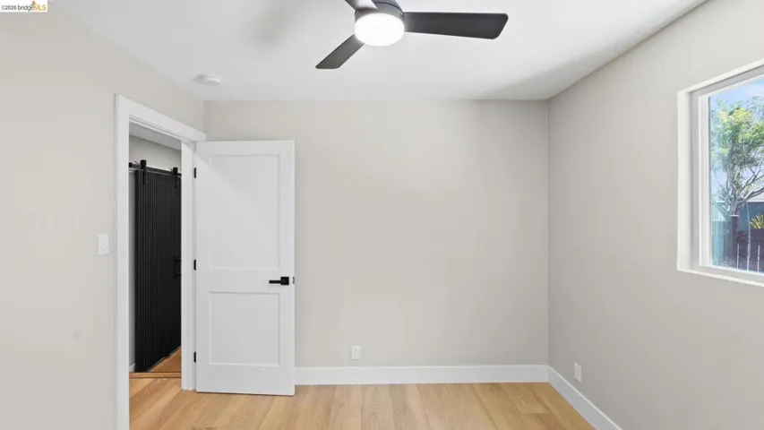 Room featuring light wood-finish flooring, a contemporary ceiling fan with light, and a white framed window