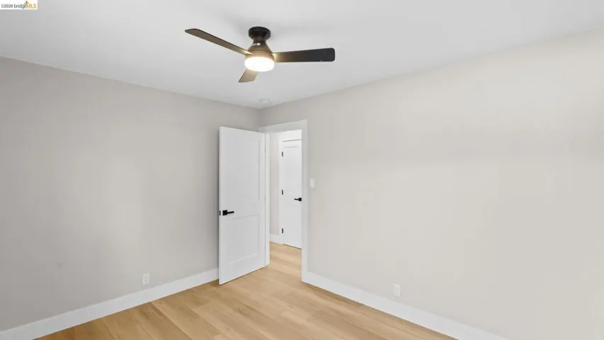 Room featuring wood-finish flooring, light-toned walls, and a modern ceiling fan with integrated lighting