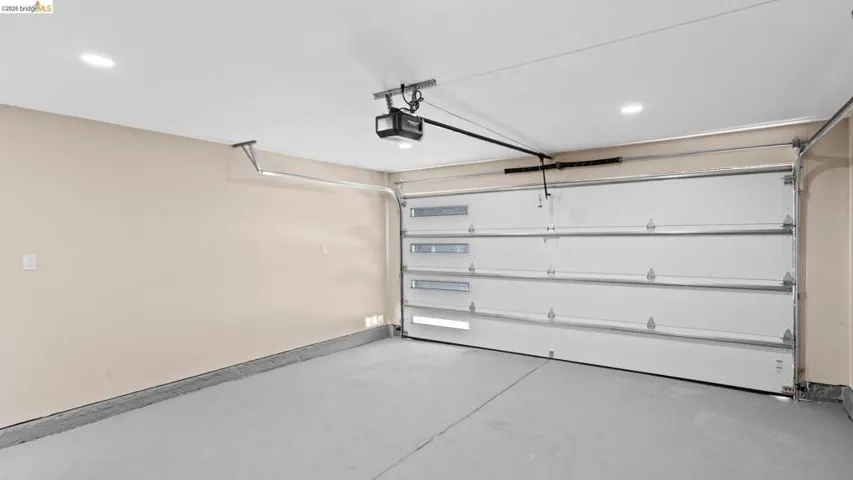 Single-car garage featuring a painted concrete floor and a white sectional garage door with horizontal lites