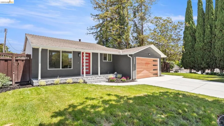 Modern-style home featuring a gray exterior, a vibrant red entry door, and a wood-finish garage door