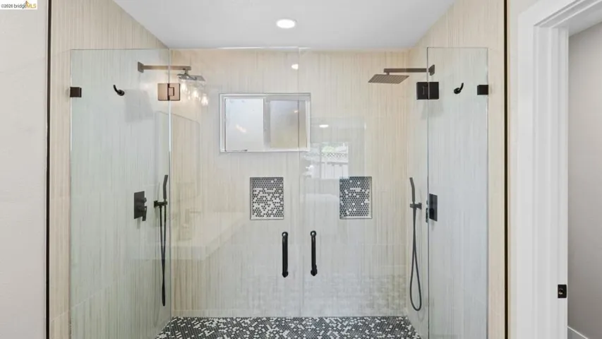 Spacious walk-in shower featuring dual glass doors and matte black hardware