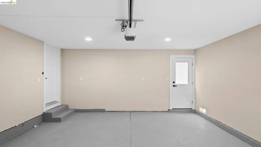 Spacious garage featuring a concrete floor, light-toned walls, recessed lighting, and a garage door opener system