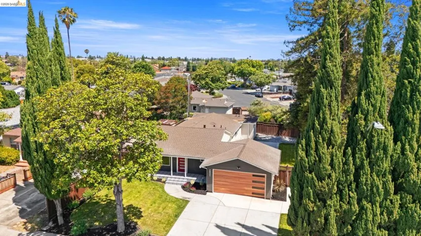 Contemporary residence featuring a dark gray exterior with a wood-look garage door and a red entry door