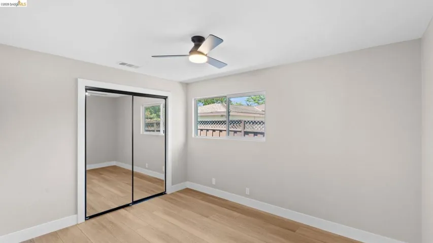 Bright room featuring wood-finish flooring, a contemporary ceiling fan with integrated lighting, and a window with natural light