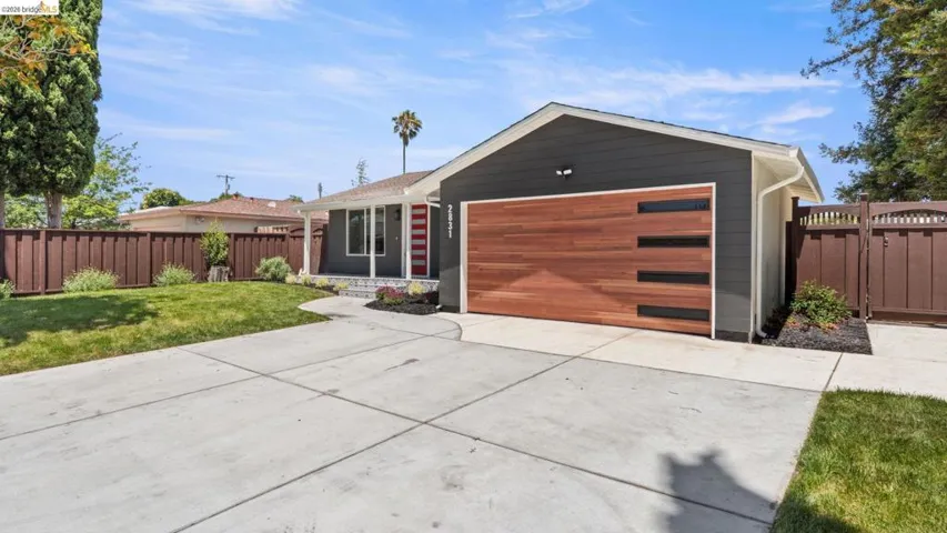 Contemporary single-story residence featuring dark gray siding and a modern wood-finish garage door with horizontal frosted glass inserts