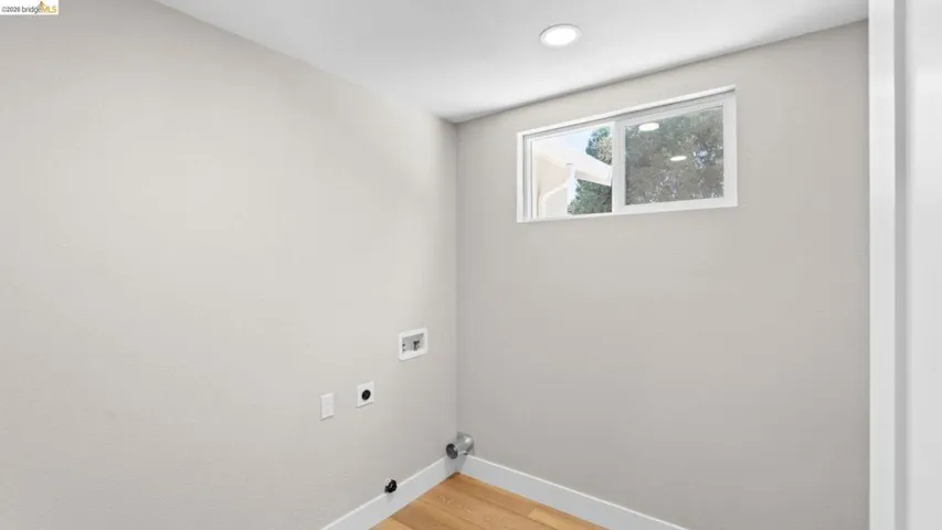 Dedicated utility space featuring a window, recessed lighting, and wood-finish flooring