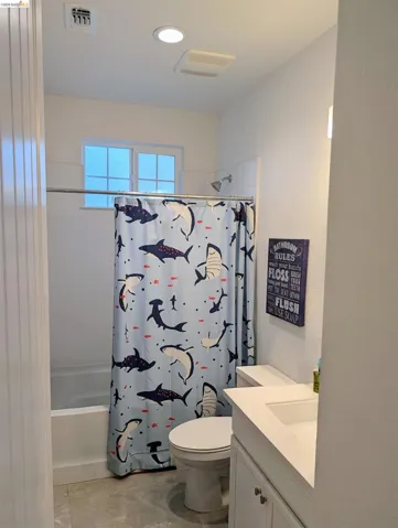 Full bathroom featuring a white bathtub with an integrated shower head, a dual-sink vanity with white countertops, a flush-mount ceiling light, and recessed lighting
