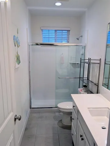 Full bathroom featuring a shower with sliding glass doors, a white toilet, and a vanity with a white countertop and integrated sink