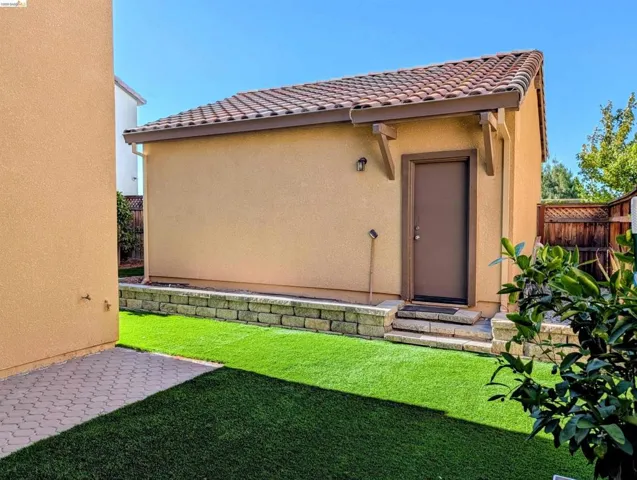 Detached structure with stucco exterior, tile roof, and a privacy door