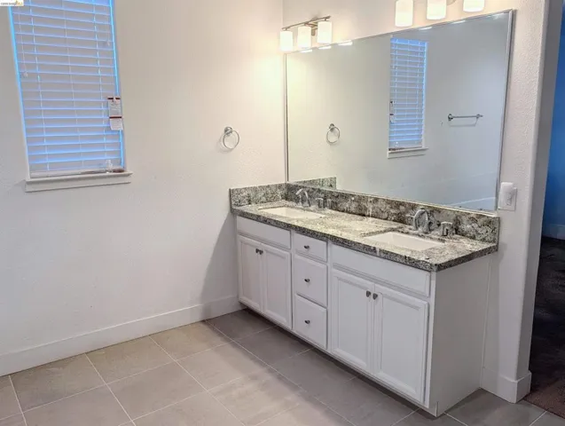 Dual vanity featuring white shaker cabinetry, granite countertops, and undermount sinks