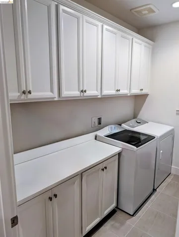 Laundry room featuring upper and lower white cabinetry, white countertops, and tile flooring