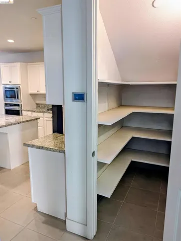 Custom-built pantry with L-shaped shelving and tiled flooring