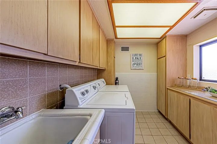 Separate laundry room featuring a sink and abundant cabinet storage