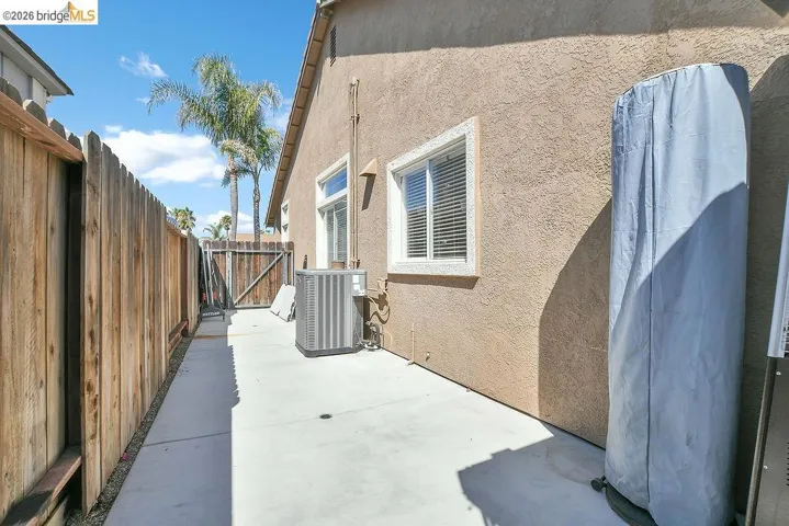 Concrete side yard with stucco exterior and a wood privacy fence