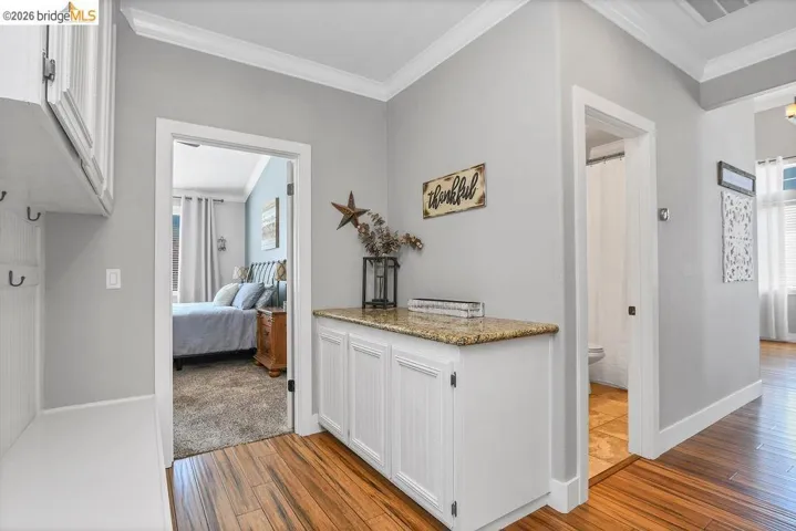 Hallway featuring wood-finish flooring, white trim, and a built-in cabinet with a granite countertop