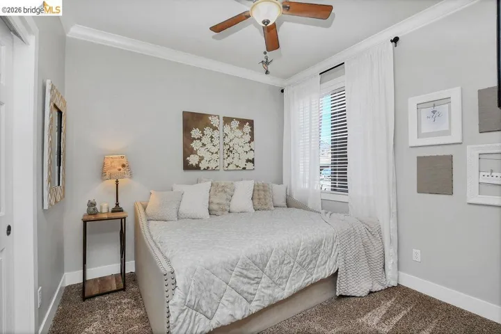 Room featuring crown molding, a ceiling fan with integrated lighting, a window with blinds and sheer curtains, and textured carpet flooring