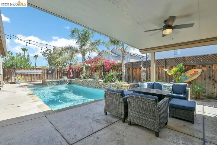 Covered patio featuring an outdoor ceiling fan, stamped concrete flooring, and string lights