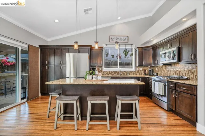 Kitchen featuring wood-finish flooring, vaulted ceilings, and dark wood cabinetry