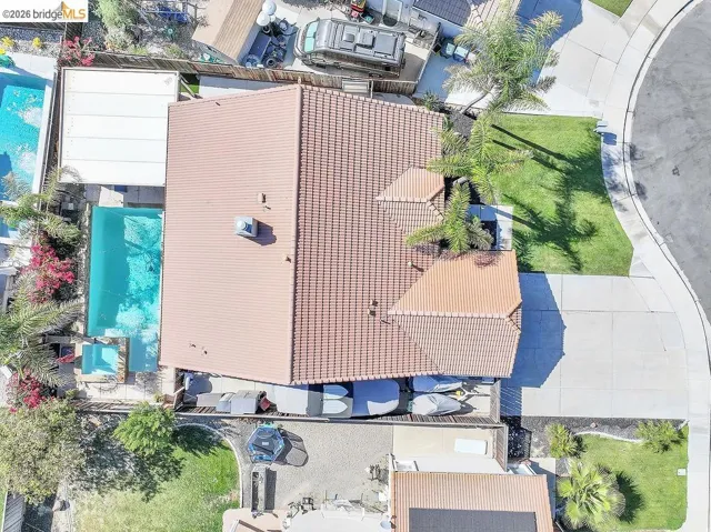 Terracotta tile roof home featuring a rectangular swimming pool, an attached spa, and a spacious concrete driveway