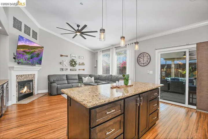 Kitchen island featuring a granite countertop, dark wood cabinetry, and pendant lighting