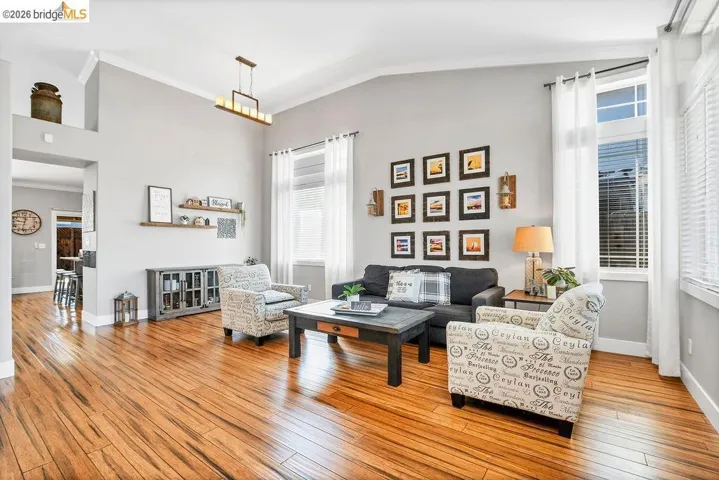 Spacious living area featuring high vaulted ceilings, warm wood-finish flooring, and crown molding