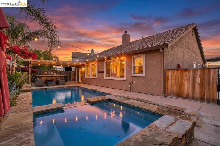 Backyard oasis featuring a swimming pool, integrated spa, and stone coping