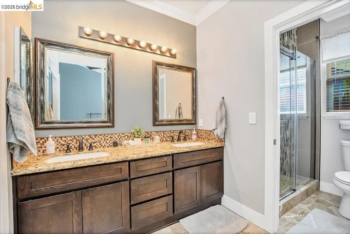 Dual vanity featuring a granite countertop, built-in sinks, and oil-rubbed bronze fixtures