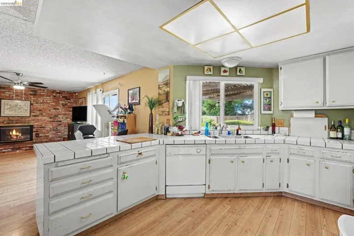 Kitchen featuring white tile countertops, white cabinetry, and wood-finish flooring