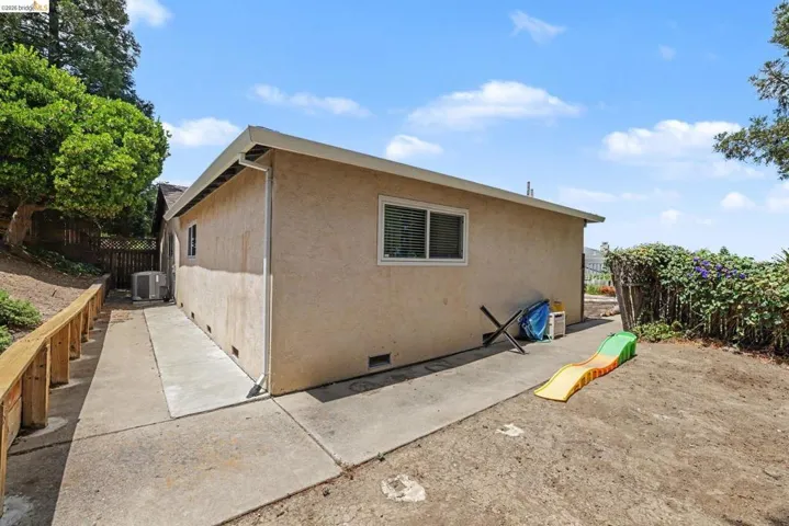 Exterior stucco siding with multiple windows and a concrete pathway