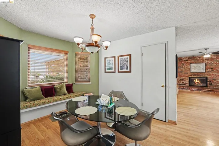 Dining area featuring wood-finish flooring, a built-in window bench, and a modern chandelier