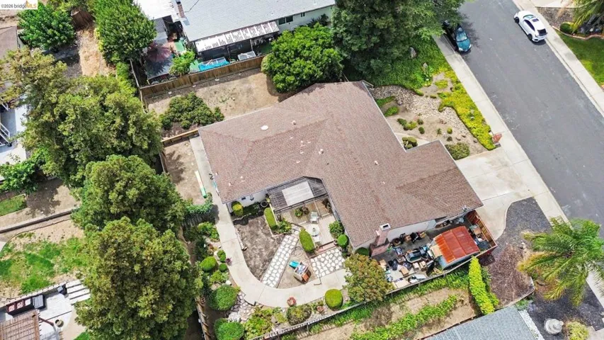 Single-story residence with a brown shingle roof, concrete driveway, and established landscaping