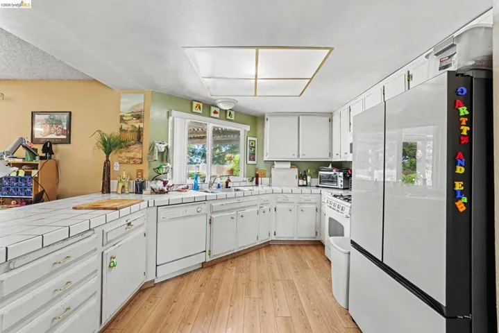 Kitchen featuring wood-finish flooring, white cabinetry, and white tile countertops