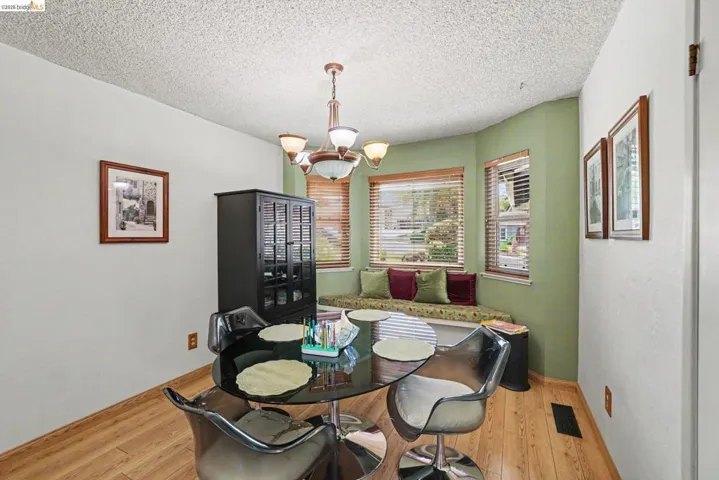 Dining area featuring wood-finish flooring, a bay window with integrated bench seating, and an overhead chandelier light fixture