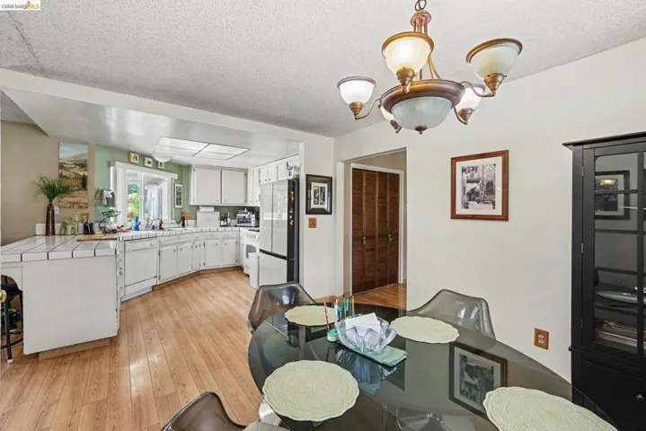 Kitchen and dining area featuring wood-finish flooring, white cabinetry, a skylight, and a tiled countertop