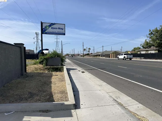 Commercial frontage featuring a concrete sidewalk and curb, with a wide asphalt roadway