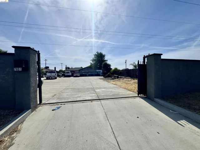 Gated entry featuring stucco pillars, a concrete driveway, and a partially developed landscape area