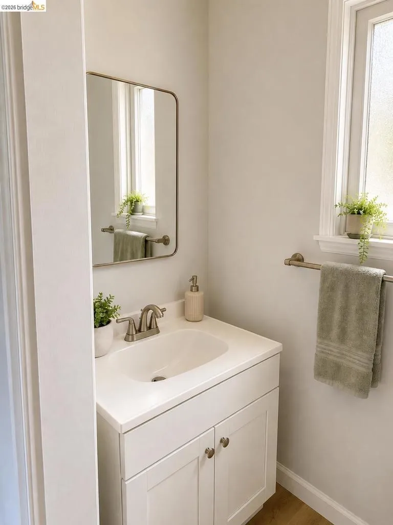 Bathroom vanity featuring white cabinetry with brushed nickel hardware, an integrated sink, and coordinating brushed nickel faucet