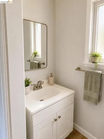 Bathroom vanity featuring white cabinetry with brushed nickel hardware, an integrated sink, and coordinating brushed nickel faucet