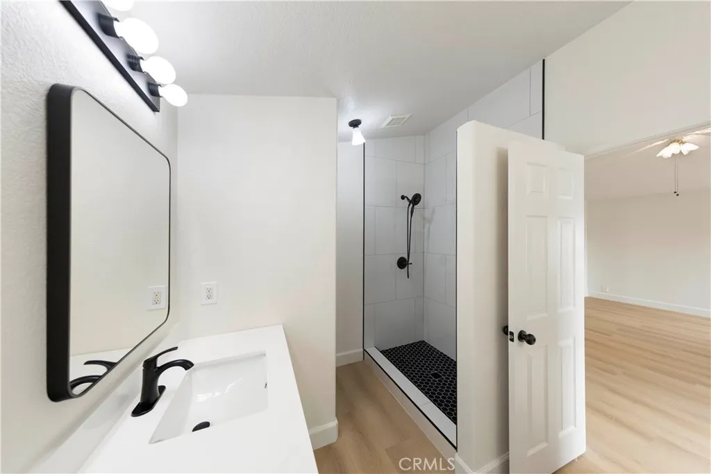 Primary bath with new walk-in shower, two vanities, mirror and light fixture.