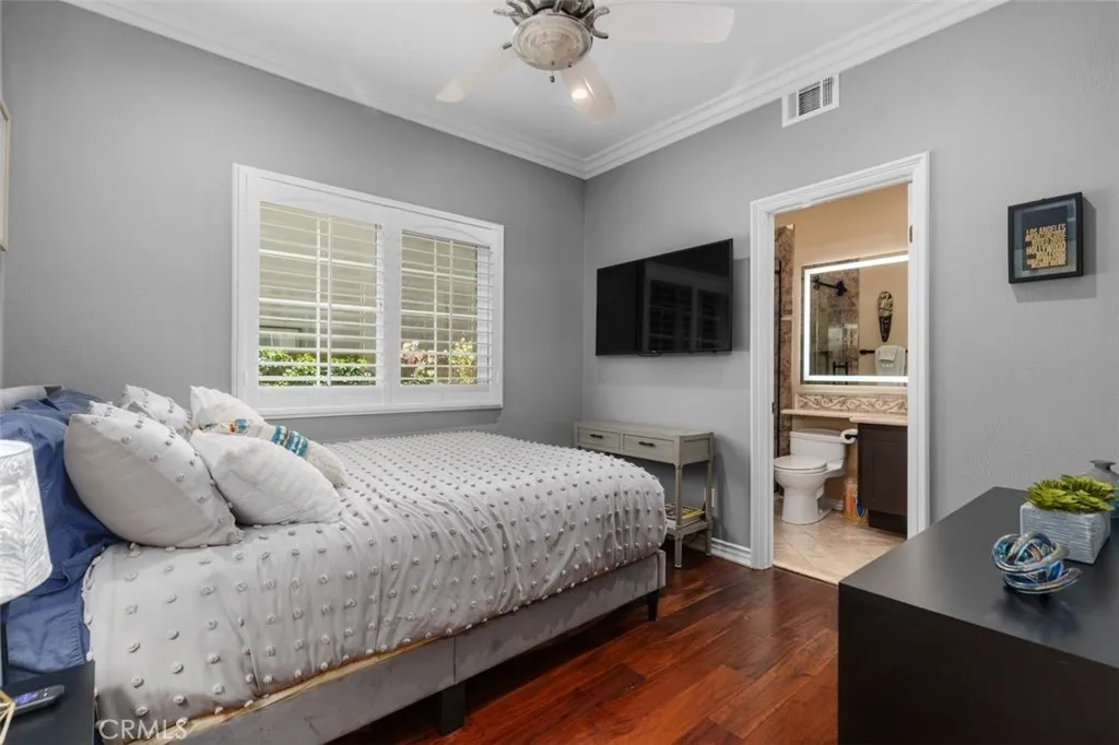 The main level bedroom with ensuite offers hardwood floors, crown molding, plantation shutters, a ceiling fan, and an updated private bath with lighted vanity mirror. This generously sized room with walk in closet is ideal for guests or multigenerational living and provides exceptional comfort and privacy.