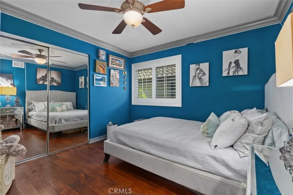 This generously sized upper level bedroom features rich hardwood floors, crown molding, a ceiling fan, plantation shutters, and mirrored wardrobe doors that add light and dimension to the space. The room offers easy access to the shared Jack and Jill bath serving the upper level bedrooms.