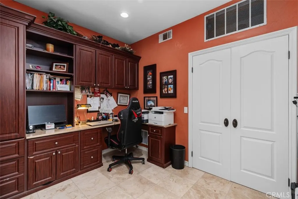 The main level library office features rich custom built in cabinetry with abundant shelving, desk space, and storage, perfectly suited for working from home or quiet study. Travertine tile floors and a closet make this a versatile space that could easily serve as an additional bedroom.