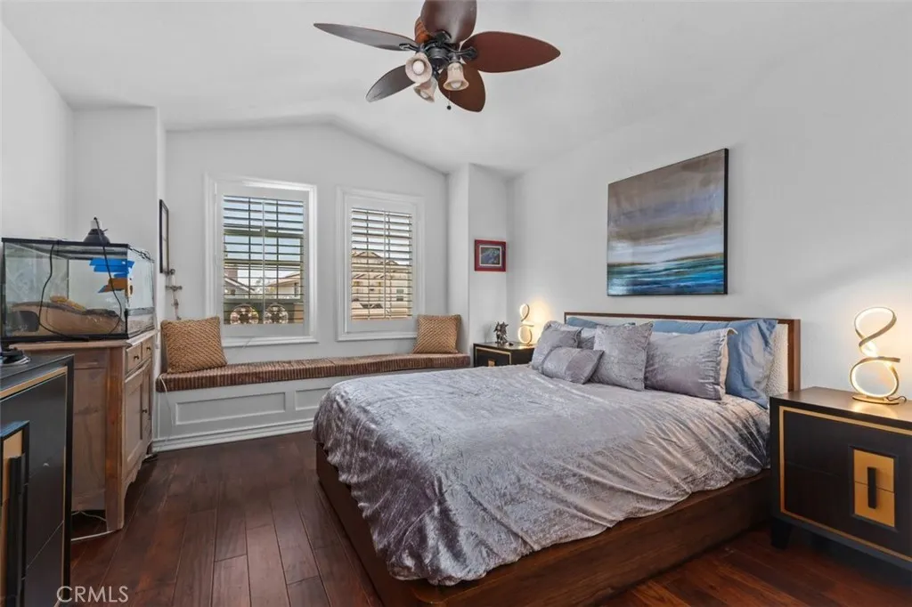 This bright and airy upper level bedroom features warm hardwood floors, vaulted ceiling, plantation shutters, a ceiling fan, and a charming built in window seat with storage below. A walk in closet and direct access to the Jack and Jill bath make this an especially desirable and functional space.